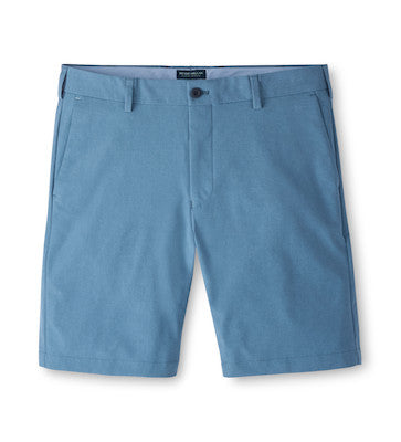 The Peter Millar Surge Short in light blue features water-resistant, four-way stretch fabric, belt loops, front button closure, and side pockets. Men’s style displayed flat on a white background.