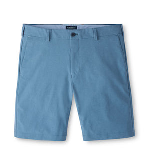The Peter Millar Surge Short in light blue features water-resistant, four-way stretch fabric, belt loops, front button closure, and side pockets. Men’s style displayed flat on a white background.