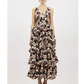 A woman stands against a white background wearing Ulla Johnson's Dephne Dress—a sleeveless, V-neck silk taffeta maxi with multi-tiered ruffle skirt and a black, pink, and cream abstract pattern.