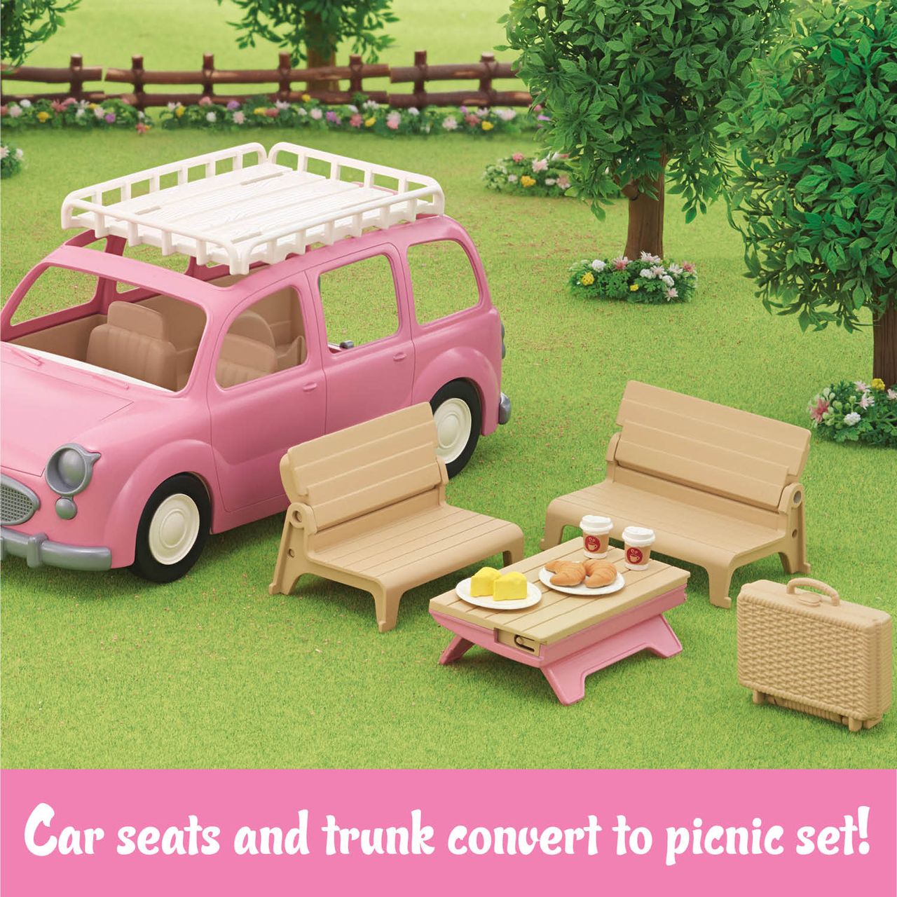Experience the perfect Family Picnic Van scene for your Calico Critters adventures: the pink Calico Critters Family Picnic Van features beige seats and a removable trunk that transforms into benches and a table with food and picnic accessories, set up on grass near a suitcase and trees.
