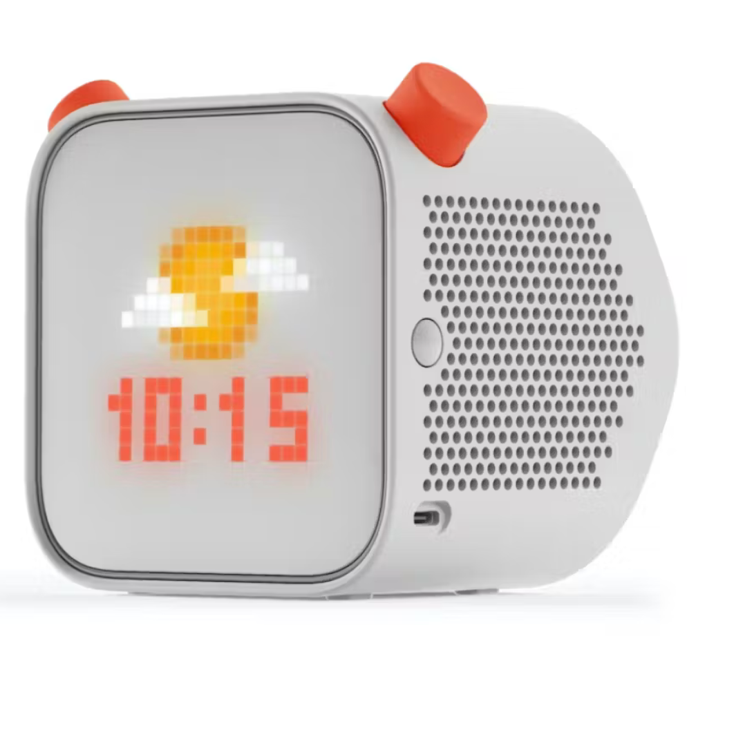 Resembling a Yoto Player, this kid-friendly digital clock features a pixelated weather display with a sun partially obscured by clouds next to the time 10:15. Its white body, orange knobs, and perforated speaker section make it an ideal addition to any child's room.