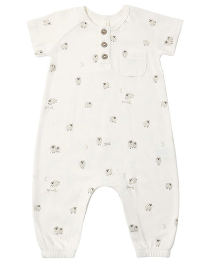 The Quincy Mae Baby Short Sleeve Jumpsuit features a white design adorned with small gray sheep patterns, a chest pocket, three coconut buttons down the front for easy changes, and elastic cuffs at the ankles.