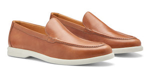 The Excursionist Leather Venetian Loafer by Peter Millar in light brown leather features white rubber soles. This pair of lightweight Brazilian loafers is displayed at a slight angle on a plain background.