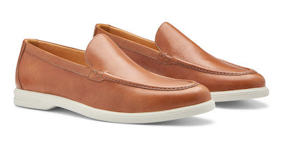 The Excursionist Leather Venetian Loafer by Peter Millar in light brown leather features white rubber soles. This pair of lightweight Brazilian loafers is displayed at a slight angle on a plain background.