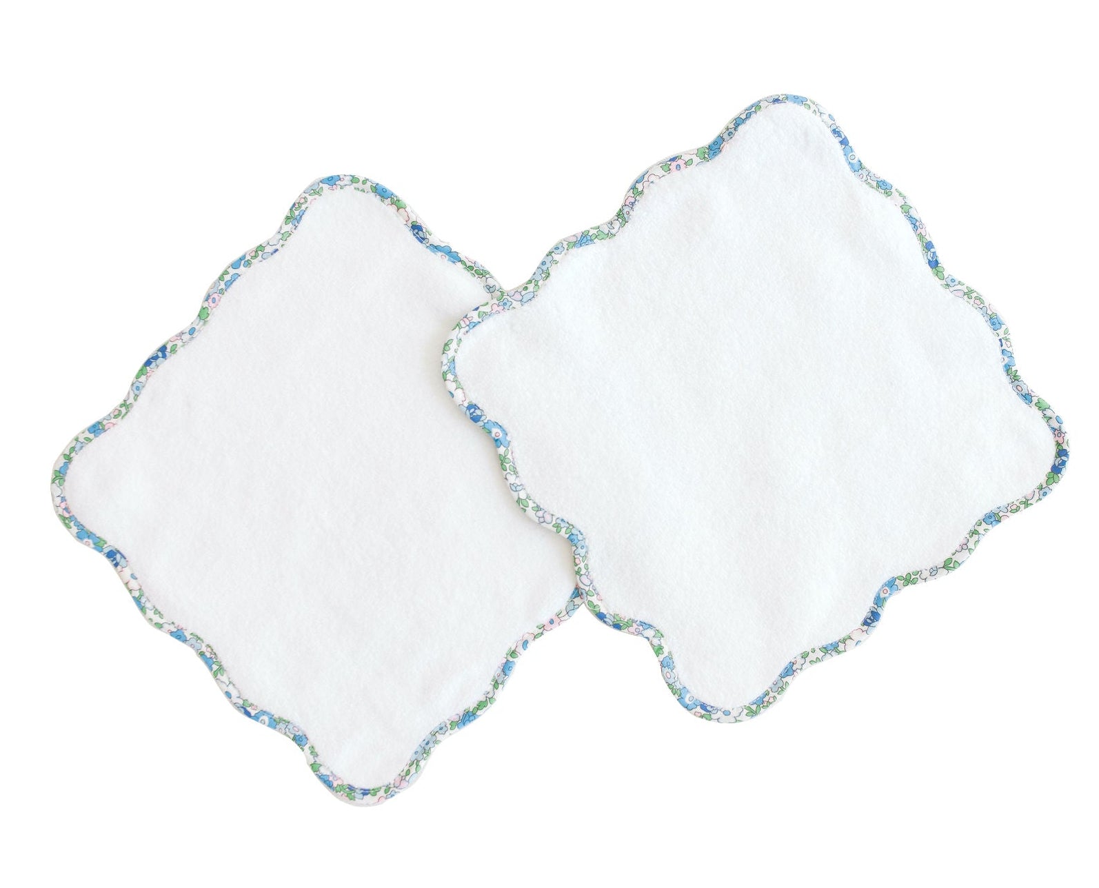 Two white wash cloths from Terry Tots, featuring delicate blue floral trim and elegant scalloped edges, slightly overlapping each other, are displayed on a white background.