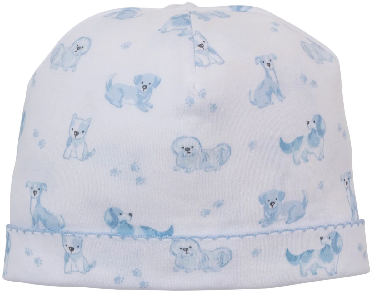 The Kissy Kissy Puppy Paws Printed Hat is a white baby hat crafted from soft Pima cotton, featuring light blue dog and puppy paw print patterns, with a stitched blue seam near the brim.