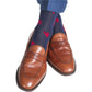 A person wearing brown leather loafers, blue trousers, and Dapper Classics Red Lobster Cotton Mid-Calf Socks featuring red motif designs made from breathable material.